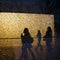 Silhouettes of walking people and trees seen through the broken window