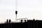 Silhouettes of workers on construction site against the sky