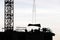 Silhouettes of workers and crane on construction site against the sky