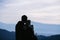 Silhouettes of young couple in love standing on the top of mountain