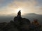 Silhouettes of young couple standing on a mountain and looking to each other on beautiful sunset background. Love of guy