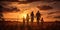 Silhouettes of a young family with children walking on a summer field against the background of a juicy sunset. The concept of the