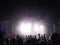 Silhouettes of young people with the raised hands up before a scene at a concert. Rock group. Bright light on the stage