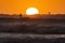 Silhoutte of kitesurfers enjoying big waves at sunset over the sun in Essaouira, Morocco. Beautiful landscape in background