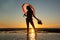 Silhoutte of a pretty senior Asian female in a swimming suit standing and hold umbrella posing on the beach.