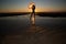 Silhoutte of a pretty senior Asian female in a swimming suit standing and hold umbrella posing on the beach.