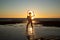 Silhoutte of a pretty senior Asian female in a swimming suit standing and hold umbrella posing on the beach.