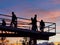 Silhouttes of people crossing a bridge with a beautiful orange sunset