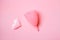 Silicone reusable menstrual cup and textile heart isolated on pink background, flat lay