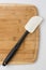 Silicone Spatula Angled on Wooden Cutting Board on White Background