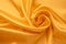 Silk background. Folds of yellow satin. Smooth shiny fabric texture, abstract bright wallpaper. Crumpled textile surface
