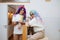 Silly looking couple in colorful wigs and sunglasses drinking tea in a kitchen