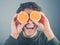 Silly young man using oranges as binoculars