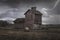 Silo barn in the rain with lightning in the sky and dark clouds in a field with a bale of hay