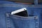 Silver aluminum smartphone placed at the male stitched blue jean`s backpocket