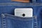 Silver aluminum smartphone placed at the male stitched blue jean`s backpocket