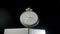 Silver antique pocket watch on a stand rotating on a black isolated background. Round gray retro clock with a white dial