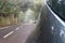 Silver auto in creepy forest and foggy route in a journey to scape, driving with safety in an asphalt mountain road. Car parked