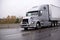 Silver big rig semi truck with grille guard transporting dry van