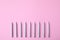 Silver birthday candles on pink background, top view