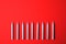 Silver birthday candles on red background, space for text