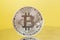 Silver Bitcoin coin on yellow . Electronic money