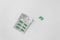 Silver blister with supplements and vitamins in green capsules on white background. Health care concept. Top view.