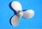 Silver boat propeller on light blue background. Small propeller used for hobby boat and yacht engines. Nautical-inspired