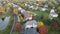 Silver car driving through a suburban neighborhood in the fall season, aerial. The Autumn colors. Aerial view of suburb. 4K