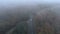 Silver car driving trough misty spooky forest, aerial drone view