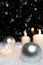 Silver christmas balls and candles in the snow, snowing background