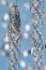 Silver christmas garland hanging on a ribbon on a blue background with bokeh