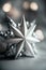Silver Christmas star on a gray background with bokeh lights.