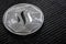 The silver coin of the Steem cryptocurrency on a gray background