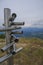 Silver-colored metal signpost in the mountains close-up across aerial mountains view. Adventure, travel lifestyle. Pietra di Bisma