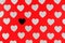 Silver confetti in the shape of heart on red background lie diagonally. And stand out black heart.