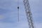 Silver crane with hook, shown with blue sky and clouds