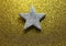 Silver five-pointed star in the glittering golden background