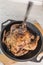 The silver fork in the defocus is stuck from above in the fried chicken, which lies in a frying pan