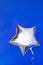 A silver glitter foil star shaped balloon on blue
