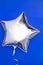 A silver glitter foil star shaped balloon isolated on blue