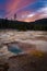 Silver Globe Cave Geyser at Biscuit basin with blue steamy water and beautiful colorful sunset. Yellowstone, Wyoming