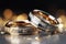 Silver and gold wedding rings sparkle on a glittery backdrop