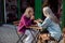 Silver haired woman tells story to mature friend sitting at table outdoors