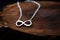 a silver infinity sign necklace on a dark wooden table