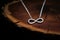 a silver infinity sign necklace on a dark wooden table