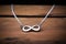 silver infinity sign necklace laying on a dark wood surface