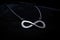 a silver infinity sign pendant against a velvet black background