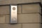 Silver intercom panel with video camera on a brick beige fence pillar of a private house