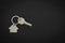 Silver key house with house shaped keychain on black leather background.